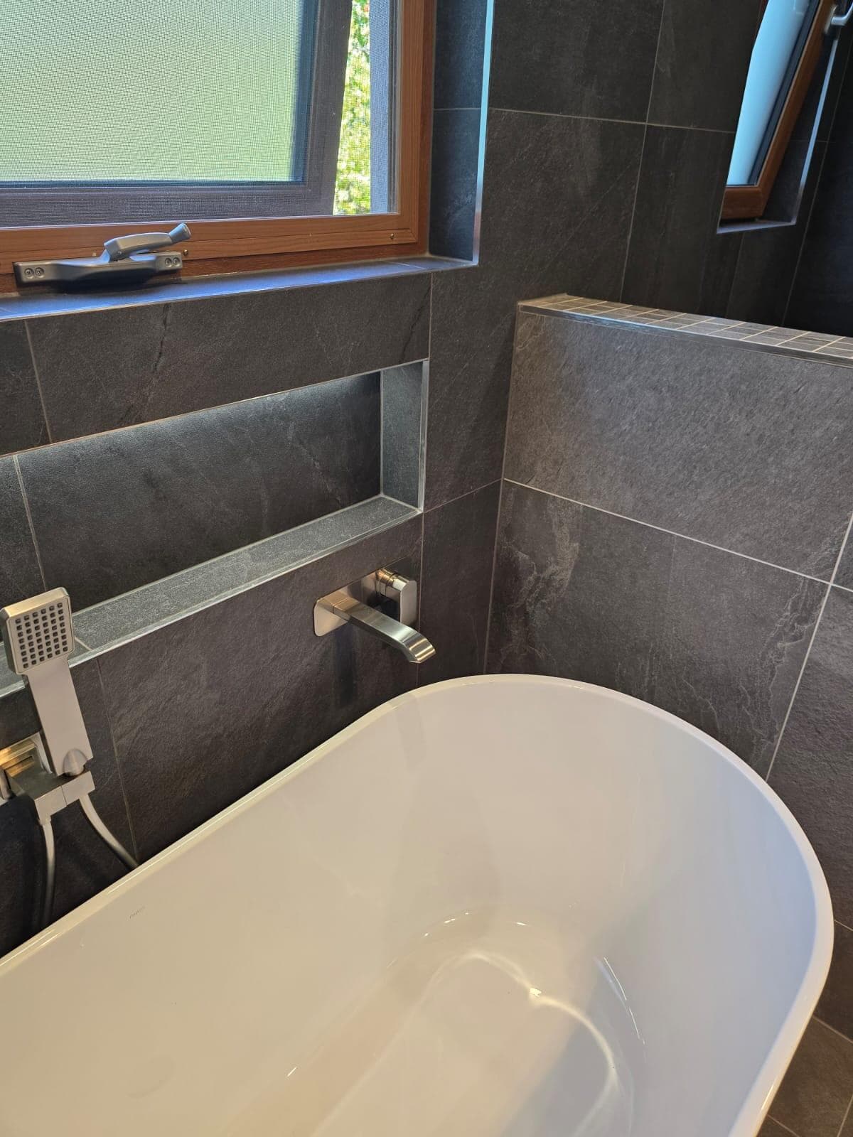 Modern bathroom renovation in Canberra with freestanding tub and dark tiles