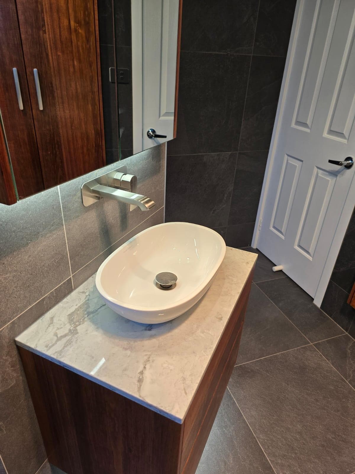 Modern bathroom renovation in Canberra with marble and dark wood finishes