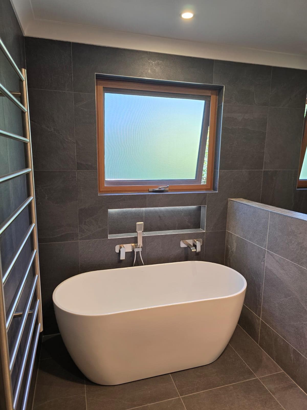 Modern bathroom renovation in Canberra with freestanding tub and sleek tiles.