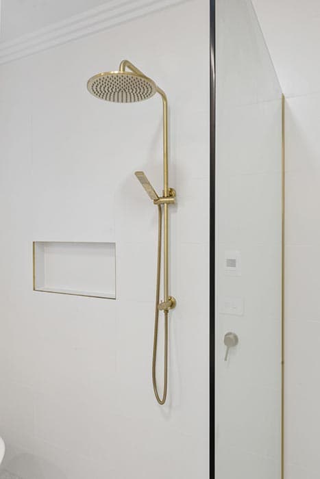 Modern shower renovation in Canberra, featuring gold fixtures and minimalist design.