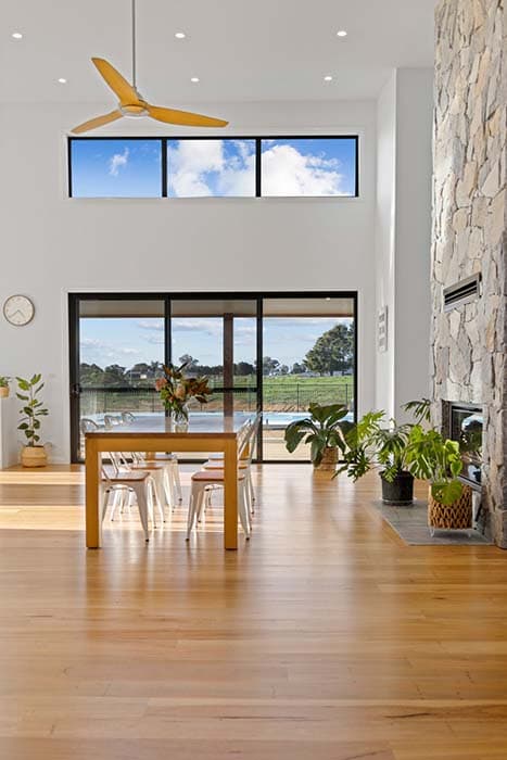 Modern dining area in a Canberra home with stone fireplace and large windows