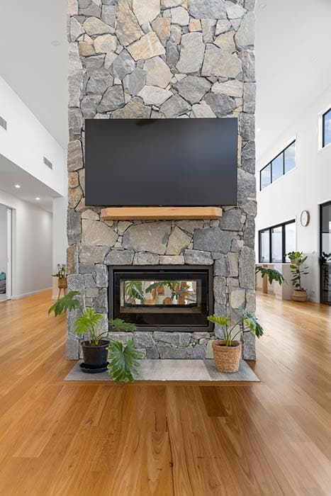 Modern living room with stone fireplace and hardwood floors in Canberra, Australia