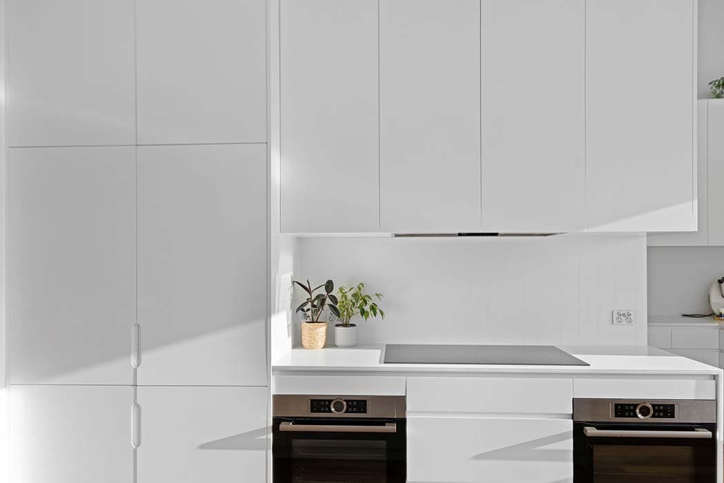 Modern kitchen renovation in Canberra, Australia with sleek white cabinetry and integrated appliances.