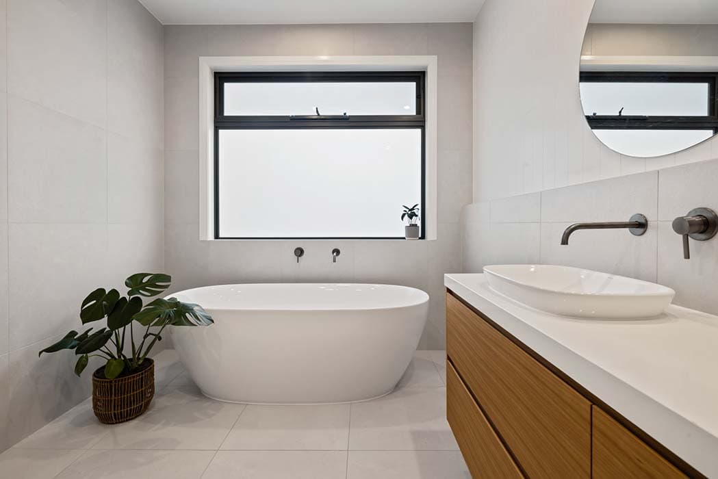 Modern bathroom renovation in Canberra with freestanding tub and wooden vanity.