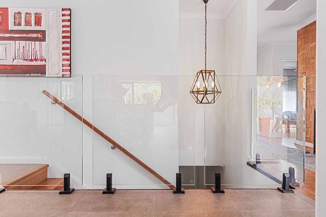 Modern entryway renovation in Canberra, showcasing glass balustrade and stylish lighting.