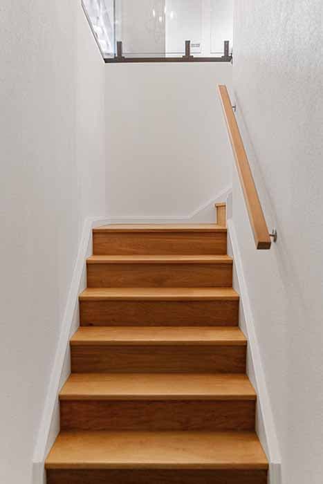 Modern staircase renovation in Canberra, Australia with wooden steps and glass balustrade.