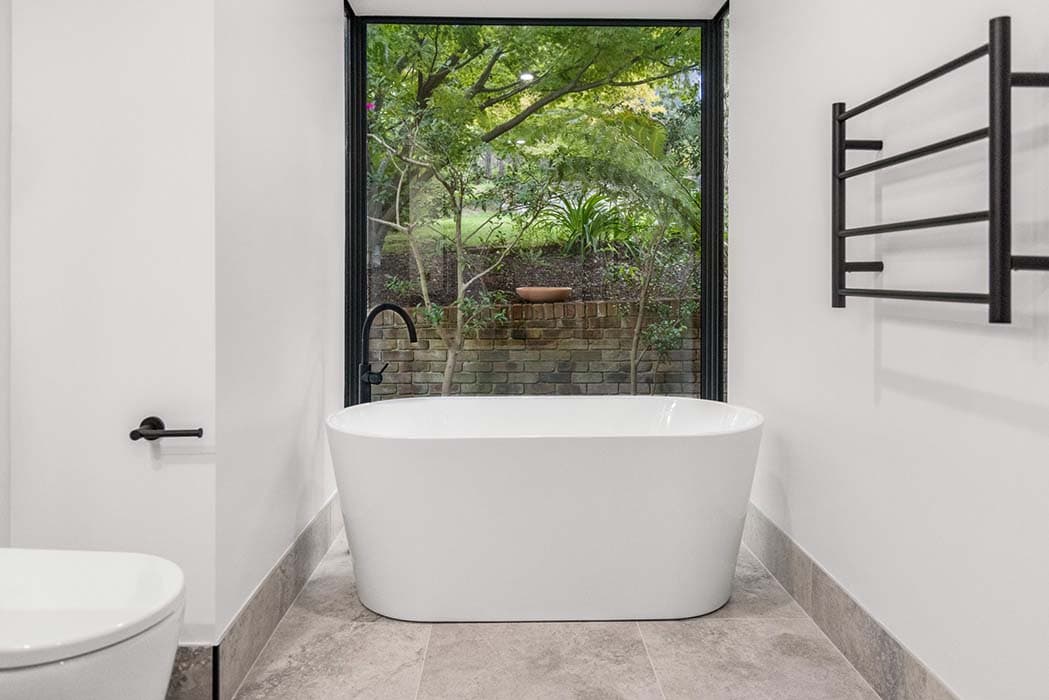 Modern bathroom renovation in Canberra with freestanding tub and garden view