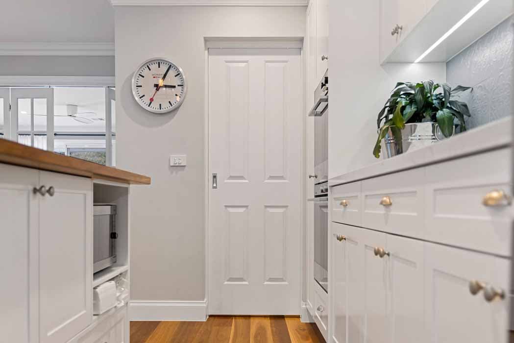 Modern kitchen renovation in Canberra, Australia with white cabinetry and wooden accents.