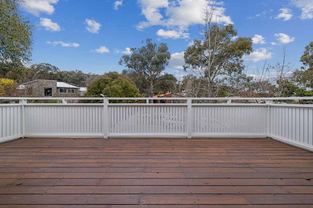 Outdoor deck renovation in Canberra, Australia with timber flooring and white railing.