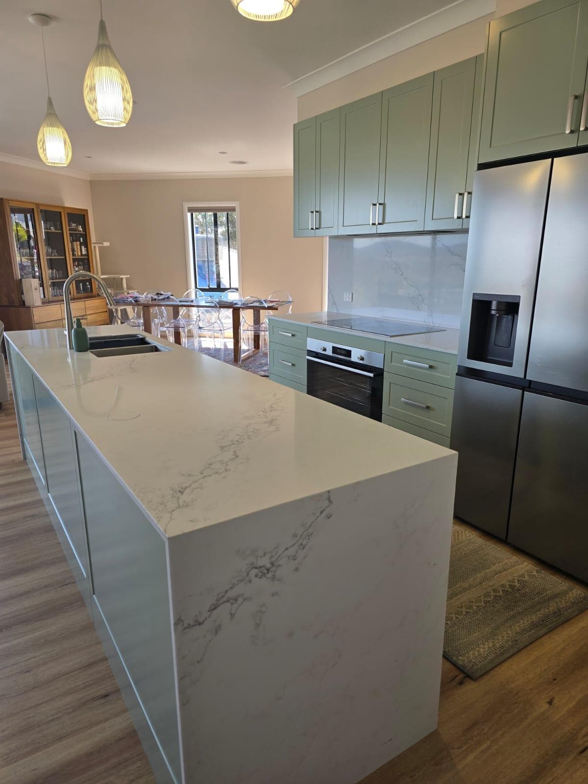 Modern kitchen renovation in Jerrabomberra, Canberra with marble countertops and green cabinetry.