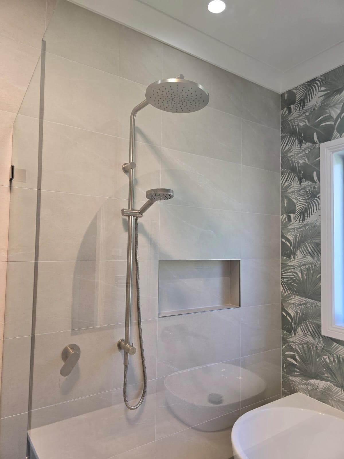 Modern bathroom renovation in Canberra with sleek fixtures and tropical accents.