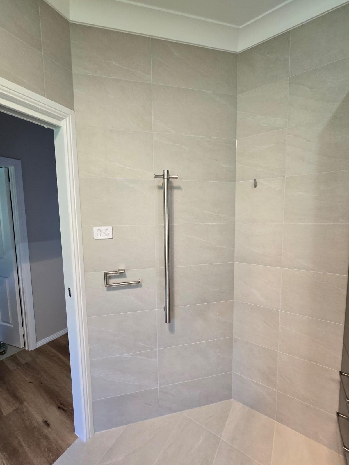 Modern bathroom renovation in Canberra with elegant grey tiles and stainless steel fixtures.