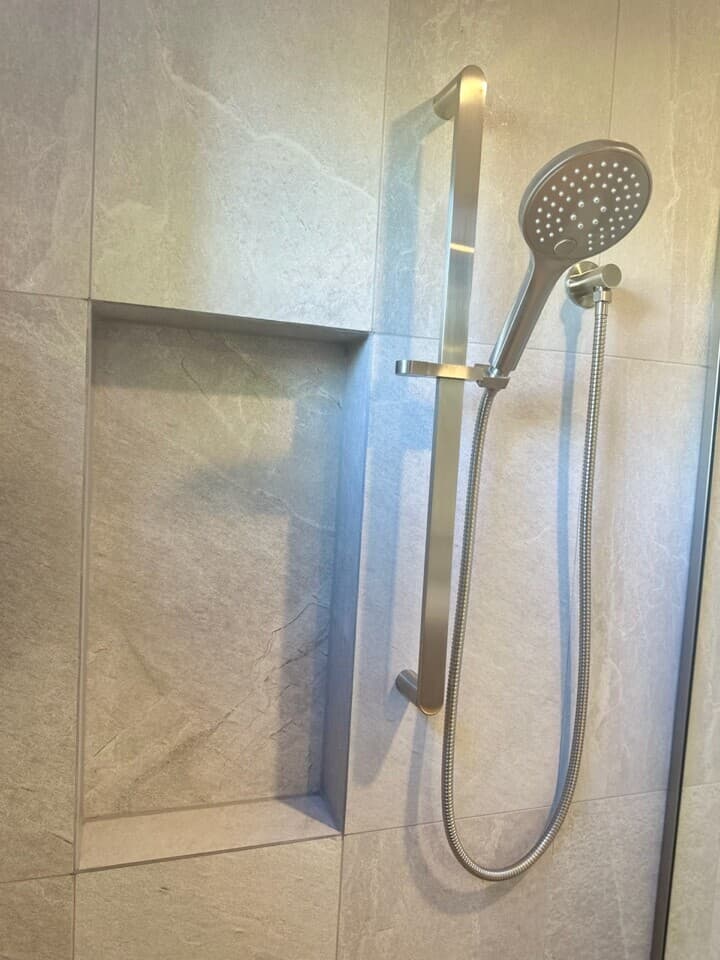Modern shower renovation in Canberra, Australia with sleek tiles and stainless steel fixtures.