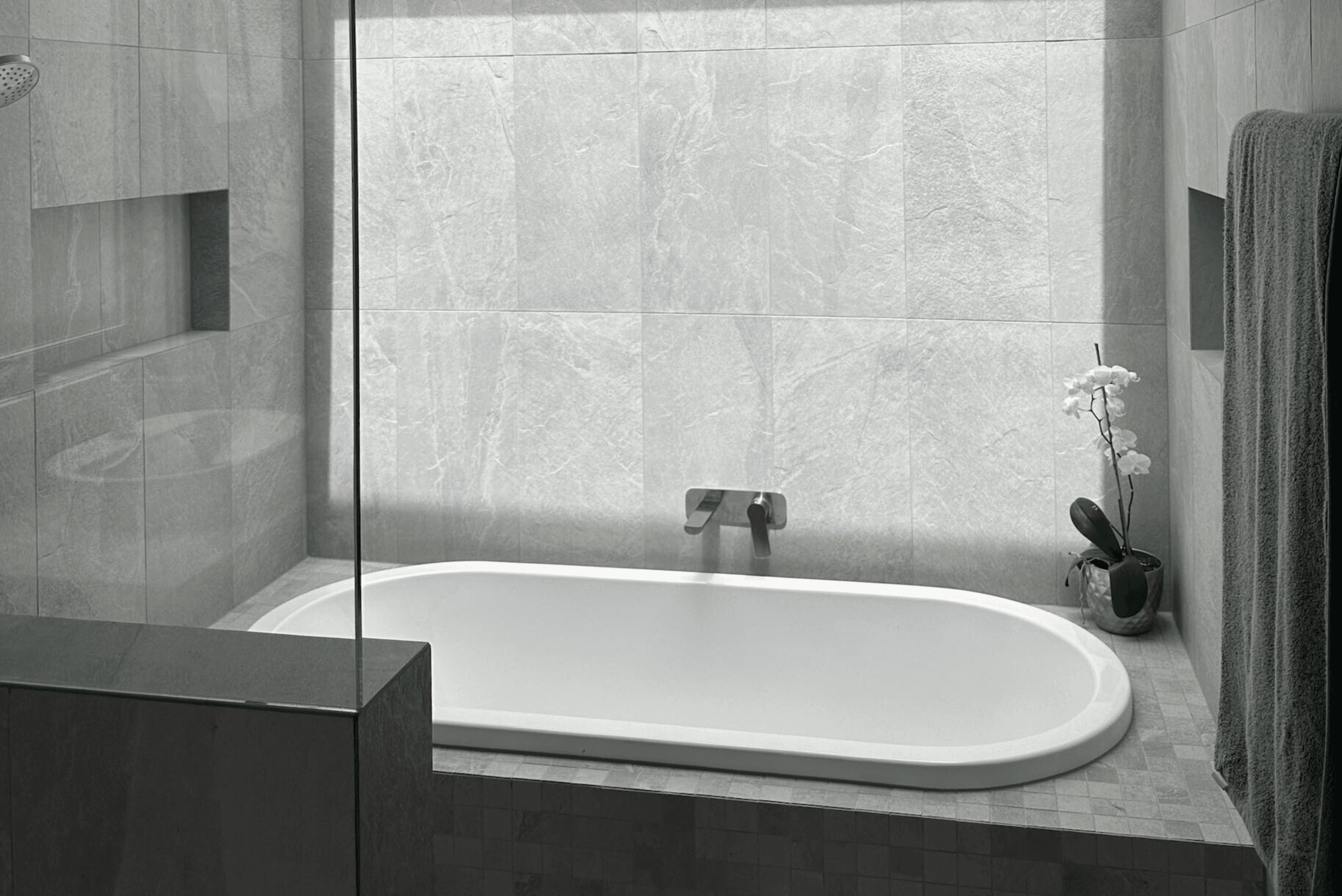 Modern bathroom renovation in Canberra with stone-look tiles and a built-in bath