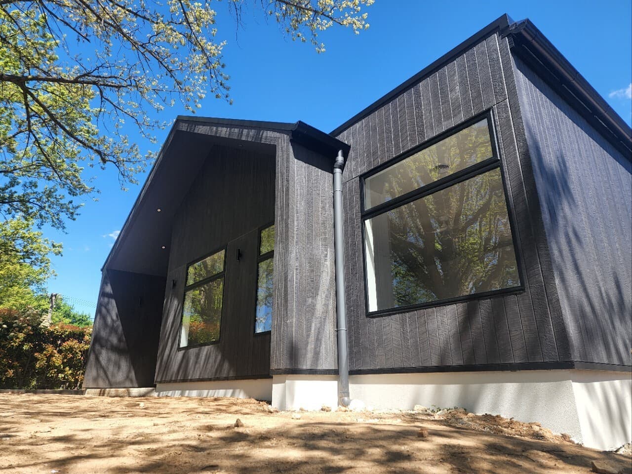 Modern new build facade with dark cladding and landscape