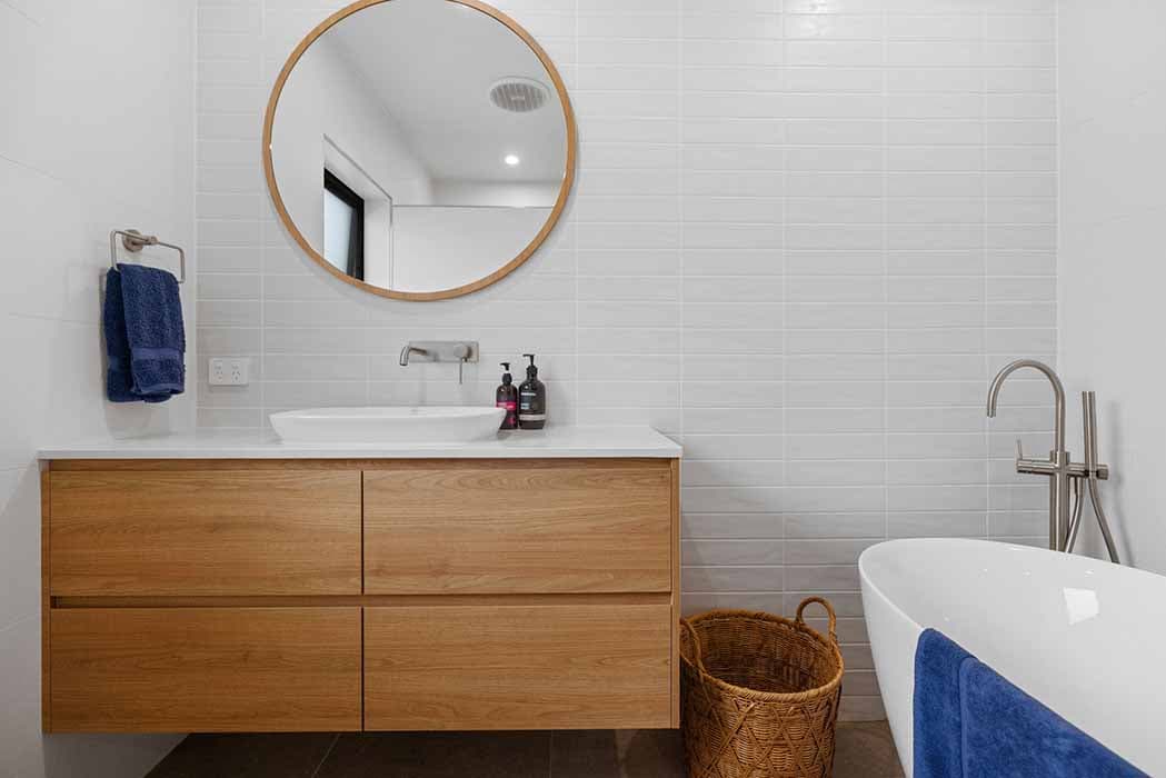 Modern bathroom renovation in Canberra with wooden vanity and freestanding bathtub.