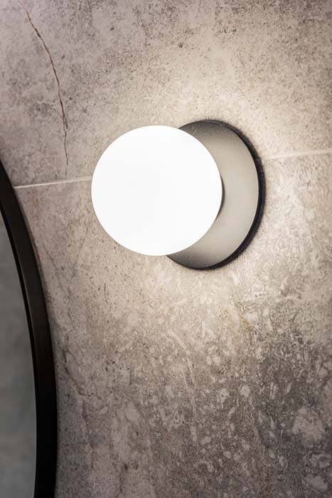 Modern wall sconce in a Canberra renovation with textured stone wall